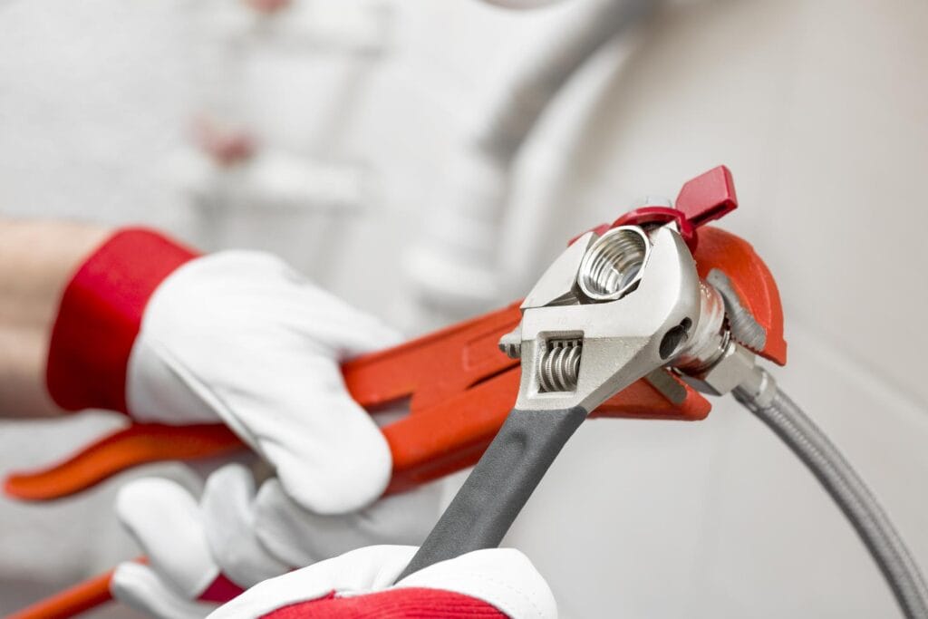 Plumber holding pipe wrenches for an emergency repair in Pittsburgh