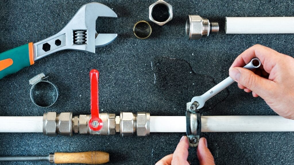 Plumber repairing a pipe valve with an adjustable wrench in Pittsburgh