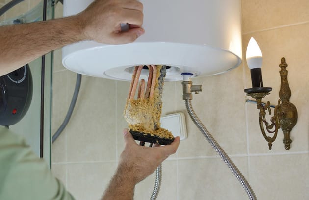 Technician removing mineral buildup from a water heater in Pittsburgh