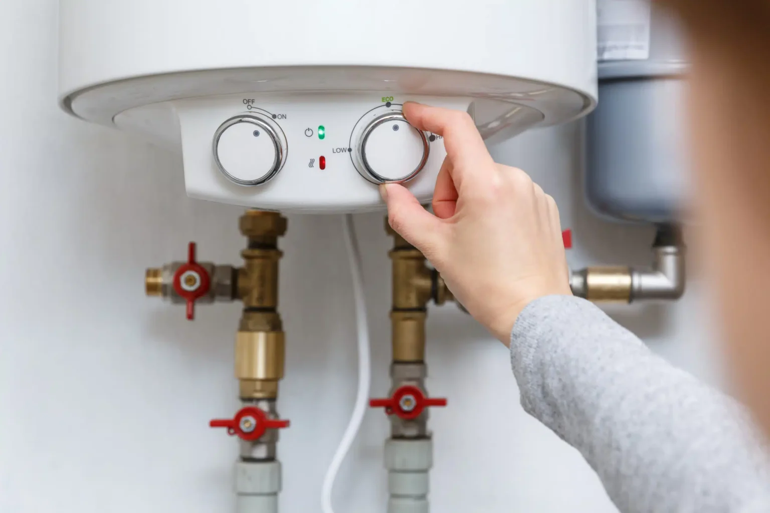 Homeowner adjusting the temperature controls on a water heater in Pittsburgh
